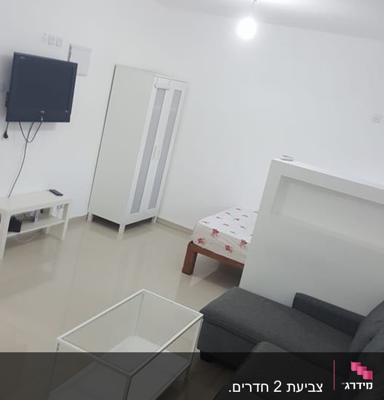 חדר עם ריהוט מודרני, טלוויזיה על הקיר, שולחן זכוכית